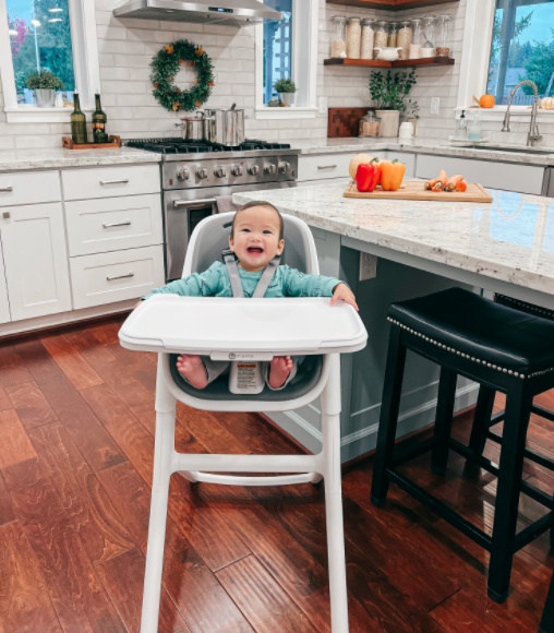 a child in the gray and white high chair