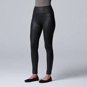 Model in black faux leather leggings with moto details on the sides 