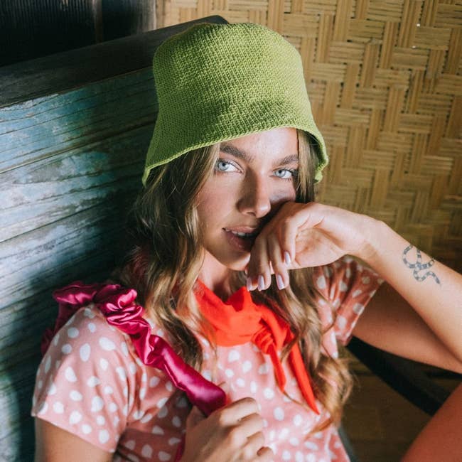 Model wearing lime green crochet bucket hat with pink and white polka dote top