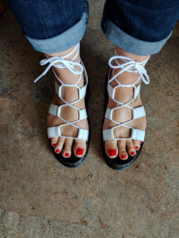 Reviewer wearing white and black lace up gladiator sandals with jeans