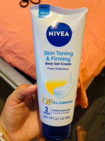 A manus holds a vessel of Nivea Skin Toning & Firming Body Gel-Cream
