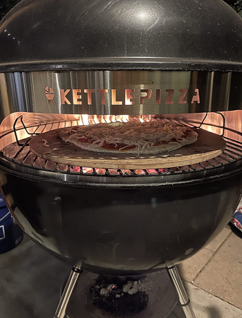 reviewer image of pizza being cooked on grill with pizza kit