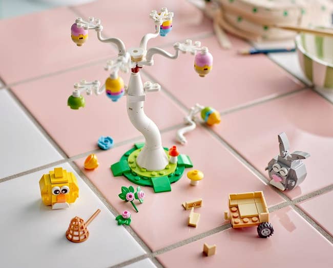 Children's toy set with a spiral tree, animal figures, and small building blocks on a tiled surface