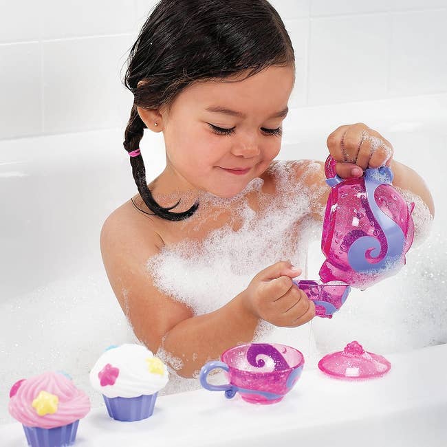 a child playing with a tea set in the bath