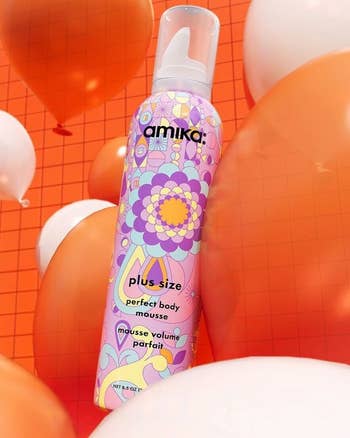 a colorful bottle of hair mousse on top of white and orange balloons