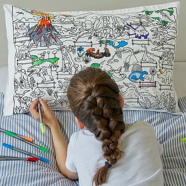 a child model coloring on a pillowcase displaying a scene of dinosaurs