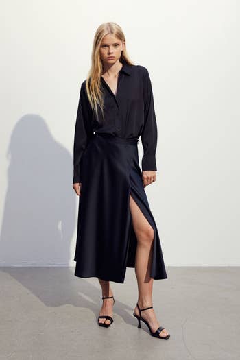 Model in a black shirt dress with a high slit and black strappy heels