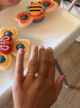 Person spins colorful butterfly fidget toys connected  a table. One manus  shows a elemental  ring