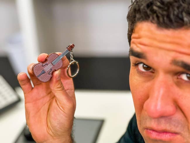model holding a small violin keychain