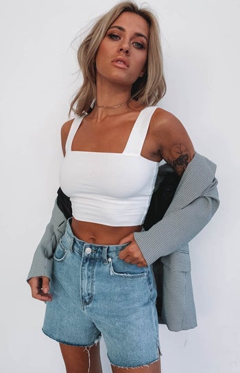model in white crop tank with blazer and jean shorts