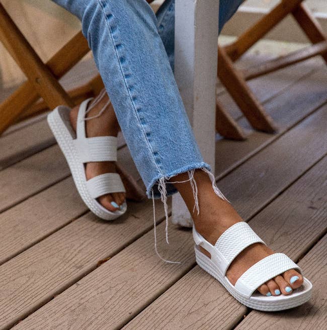 a model wearing the sandals in white 