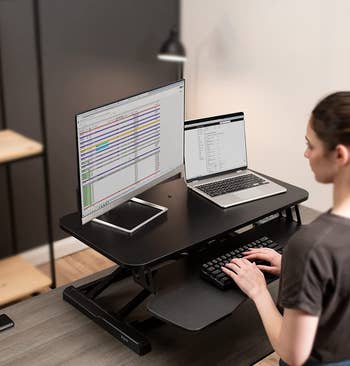 model using sit-to-stand desk converter in the standing position