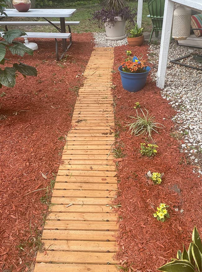 a reviewer photo of the wooden pathway laid down in a garden surrounded by wood chips 