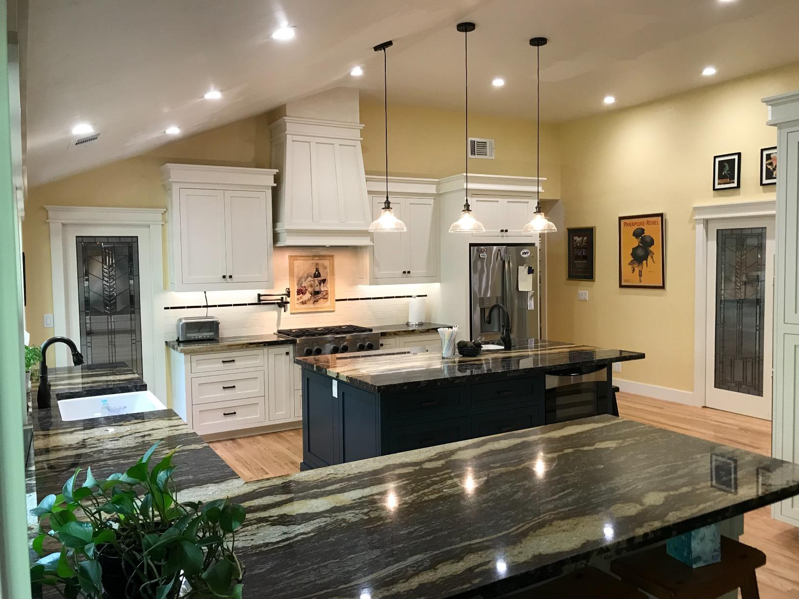 three pendant lights over black island counter in well-lit modern-looking kitchen