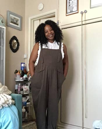 a plus size reviewer wearing the army green overalls