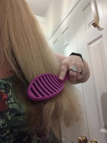 Person brushing hairsbreadth  successful  a bathroom, utilizing a purple brush. Rings are disposable   connected  fingers