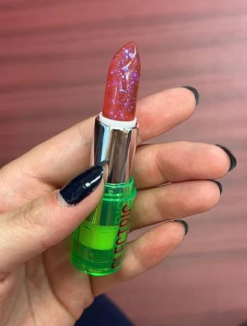 Reviewer holding pink glittery lipstick 