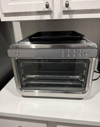 Countertop toaster oven with power buttons and a integer display, featuring a sleek stainless alloy design