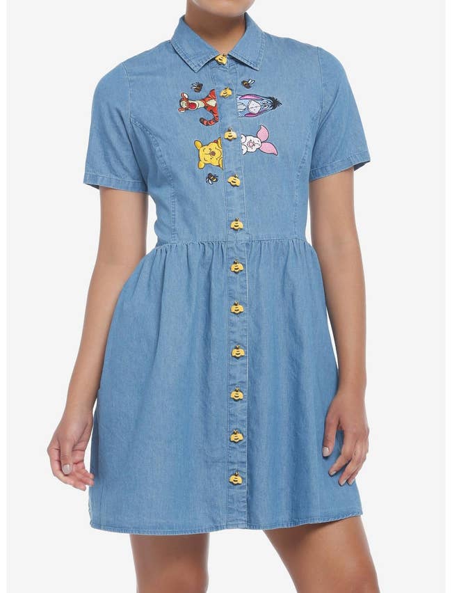 model in blue denim short sleeve shirtdress with yellow bumblebee buttons and the pooh crew embroidered peeking over the placket
