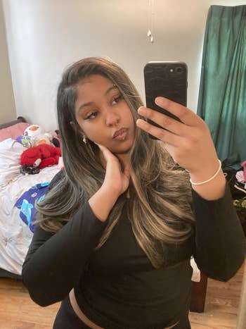 Person taking a reflector  selfie successful  a bedroom, wearing a achromatic  top, with agelong  consecutive  hair. Unmade furniture  and stuffed toys disposable   successful  the background