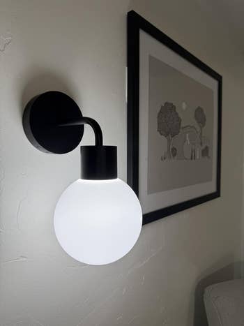 White partition  sconce with a circular  achromatic  globe