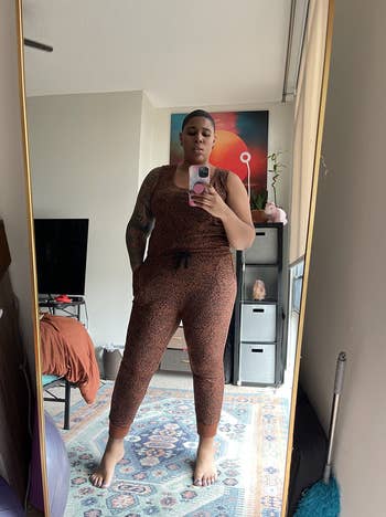 a reviewer wearing the jumpsuit in the dark camel/black ikat print