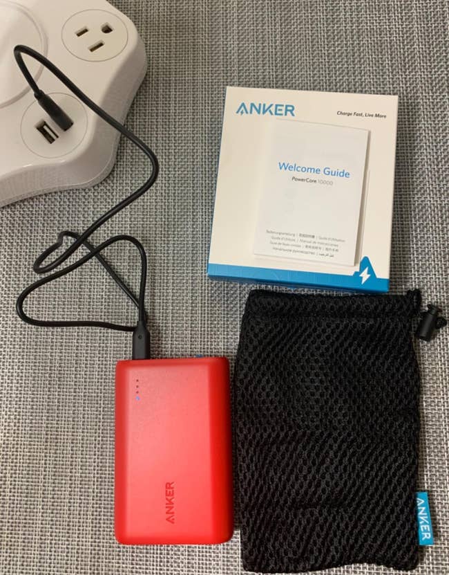 Reviewer's portable charger next to carrying case and welcome guide