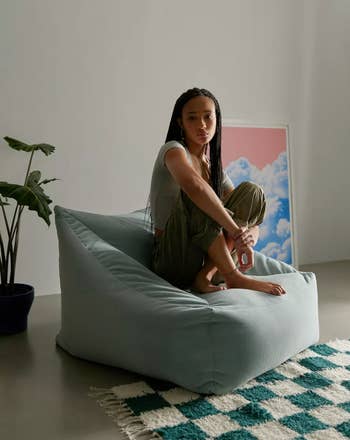 model sitting on a light blue beanbag chair 