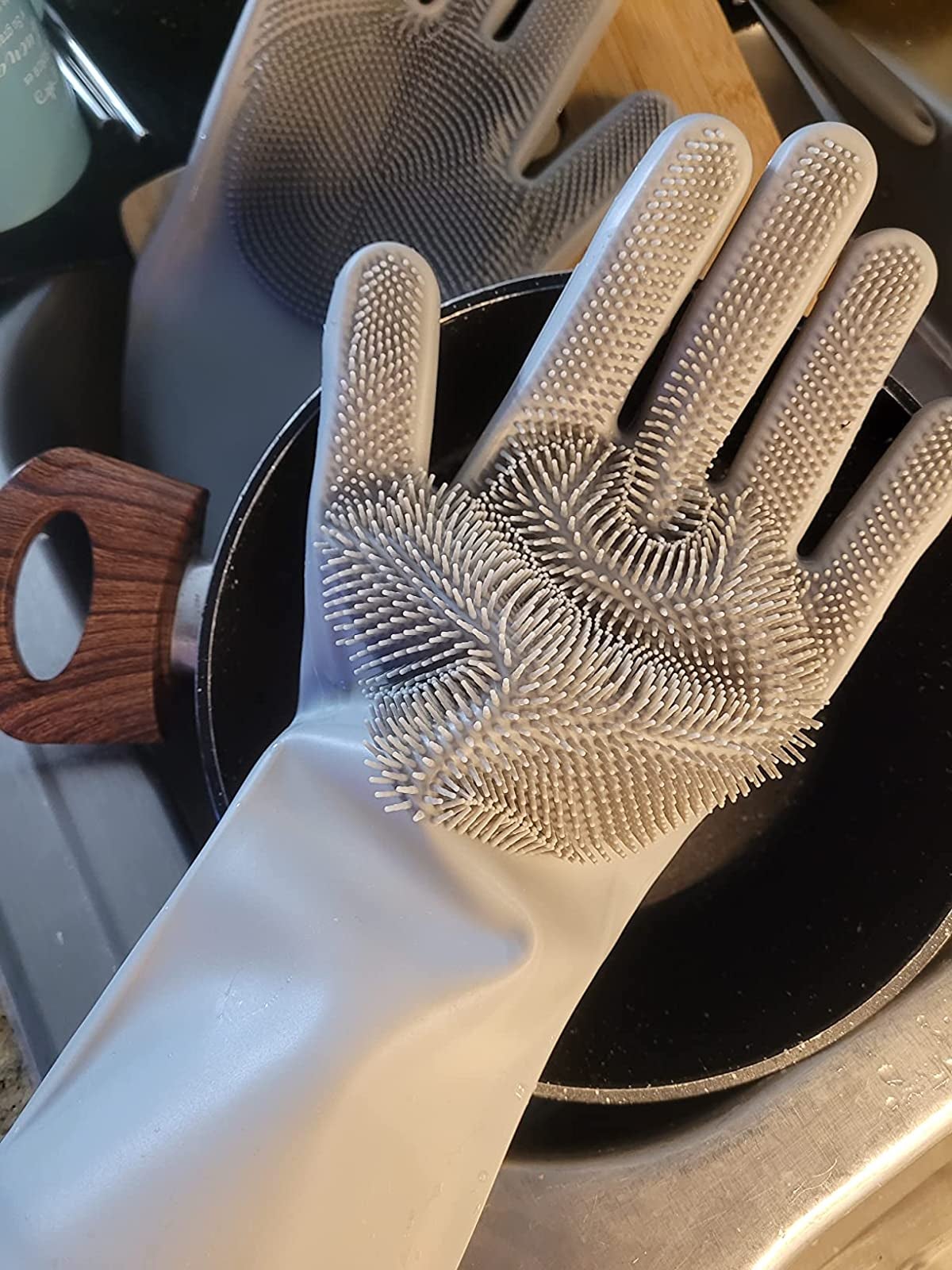 reviewer photo of them wearing the gray gloves above a sink of dishes