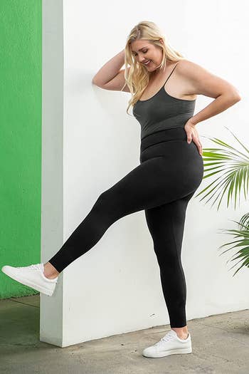 model wearing the black leggings with a tucked in cami and white sneakers