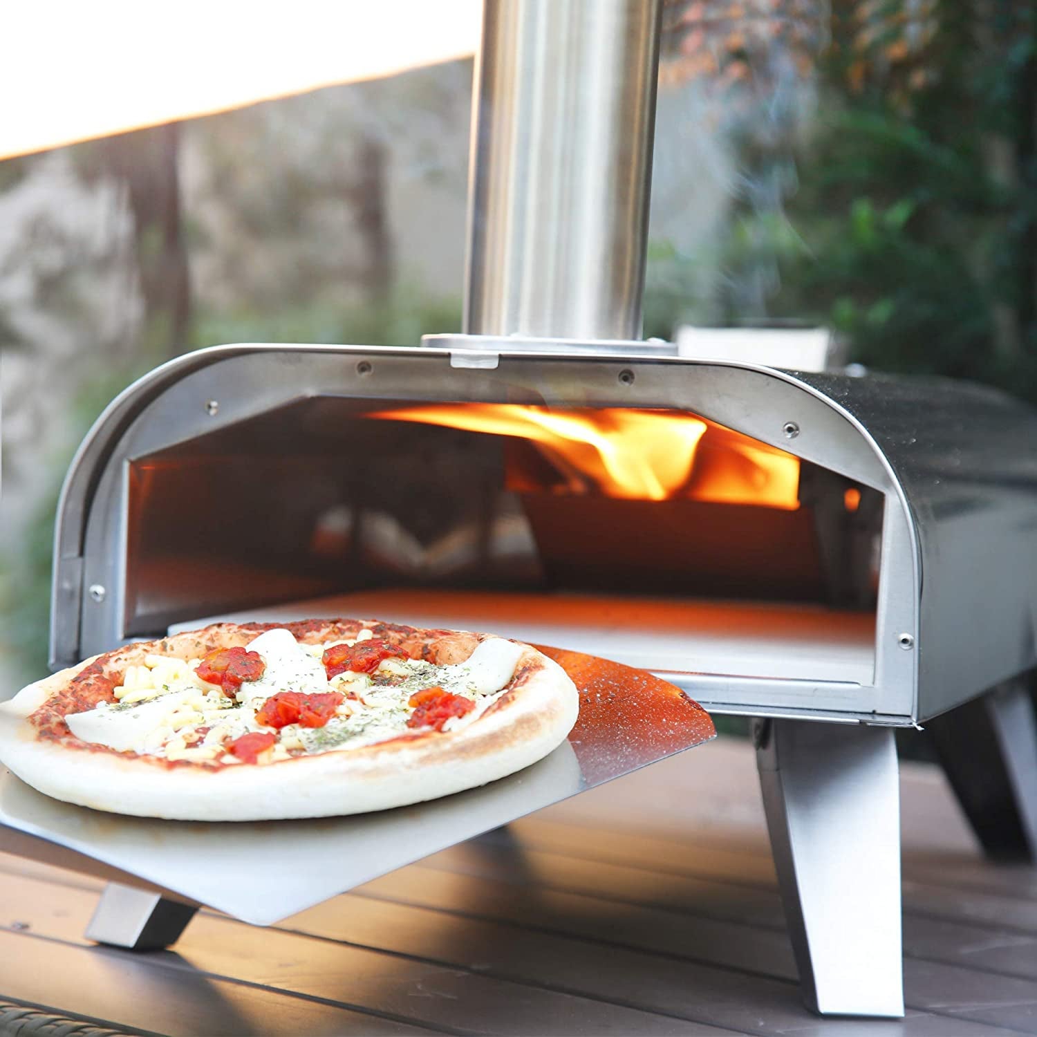 the lit pizza oven outside with a pizza coming out of it