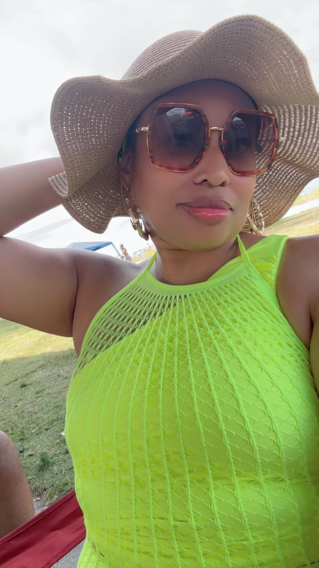 Person successful  a stylish sunhat and ample  sunglasses, wearing a textured halter top, posing outdoors