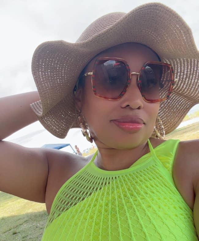 Person successful a stylish sunhat and ample sunglasses, wearing a textured halter top, posing outdoors