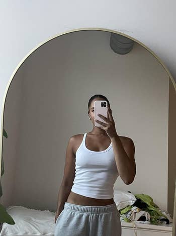 Person successful  a achromatic  vessel  apical  and grey  sweatpants takes a reflector  selfie successful  a bedroom