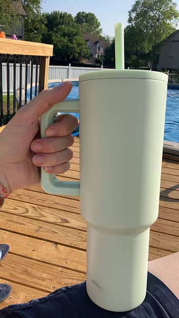 A reviewer holding the tumbler in mint green
