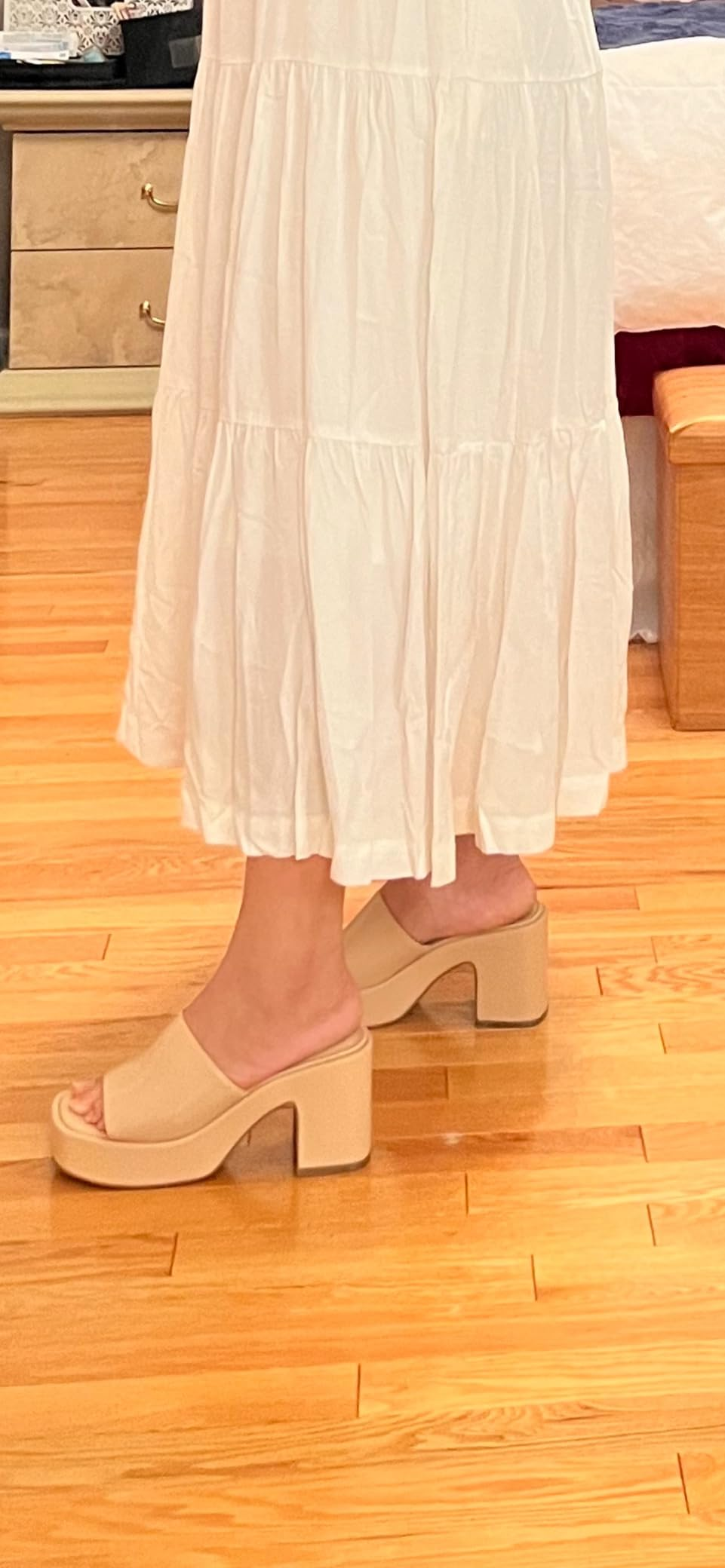 Person wearing beige block-heeled sandals and a long, flowing skirt indoors