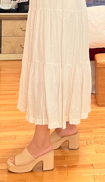 Person wearing beige block-heeled sandals and a long, flowing skirt indoors