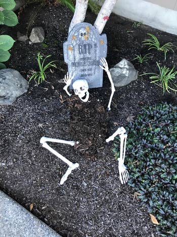 a skeleton with its arms and legs sticking out of the ground next to a grave