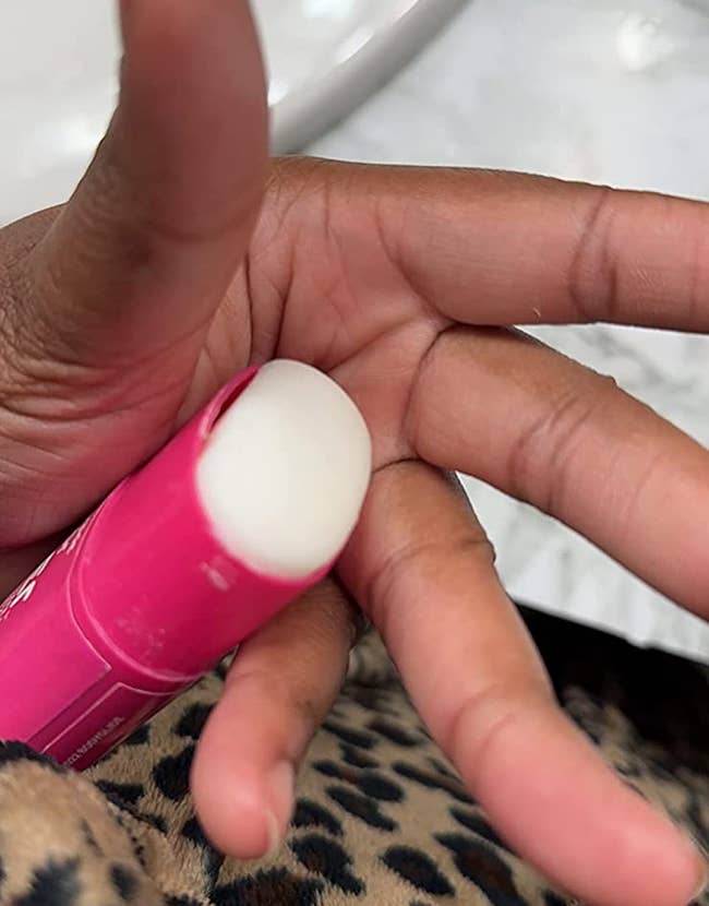 Reviewer displaying pink tube with white balm on inside