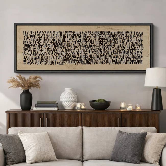 Abstract black-and-white wall art above a wooden console, decorated with vases and candles, enhancing modern living room decor
