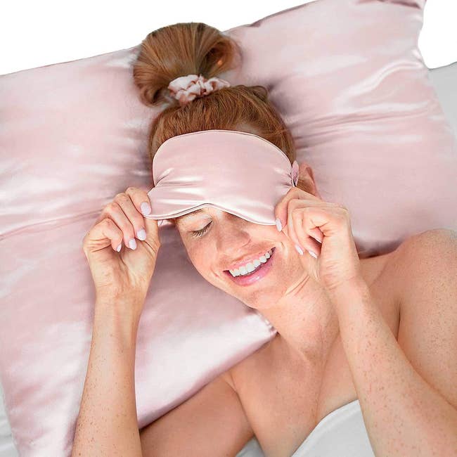 a model laying on a pink satin pillowcase