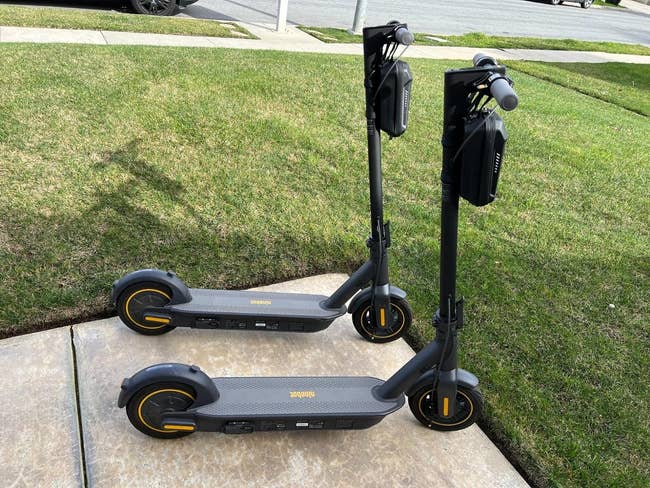 Two black electric scooters parked on a sidewalk