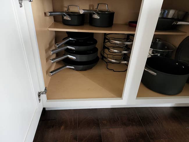 Inside of a reviewer's cabinet with four pans stacked and another shelf stacked with lids