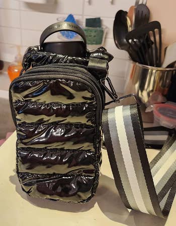 a reviewer photo of the bag in black with a water bottle inside 