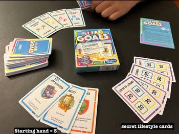 A board game setup with Life Goals cards, including starting hand and secret lifestyle cards, is ready to play