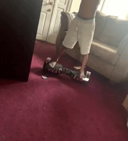 Reviewer riding silver chrome hoverboard on red carpet