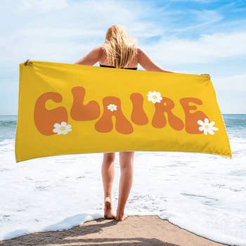 a person holding up a yellow towel with the name Claire largely printed on it