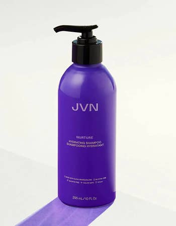 Purple bottle of shampoo with black pump on a white background