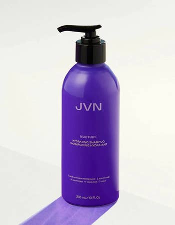 Purple bottle of shampoo with black pump on a white background