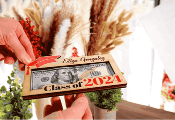 gif of a hand pulling a hundred-dollar bill out of a wooden graduation frame 